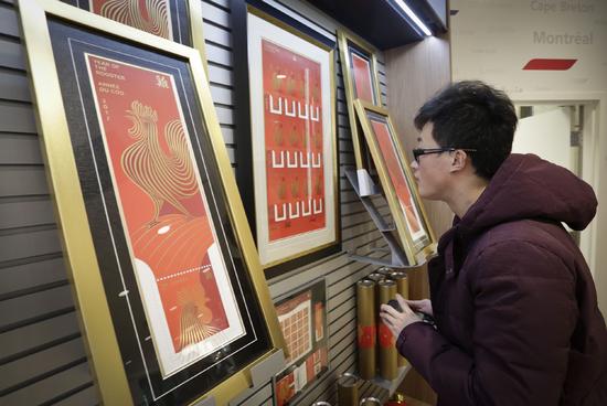 一名男子在一家邮局欣赏中国鸡年生肖邮票相关纪念品