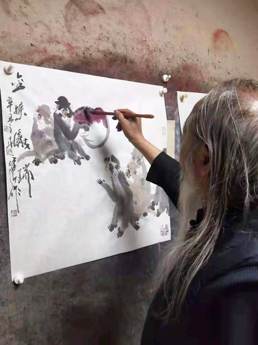 画家徐培晨在创作写意花鸟画作品金猴献瑞